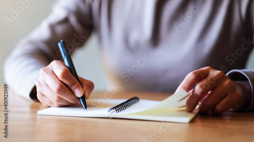 Closeup image of a woman writing on a blank notebook on the table