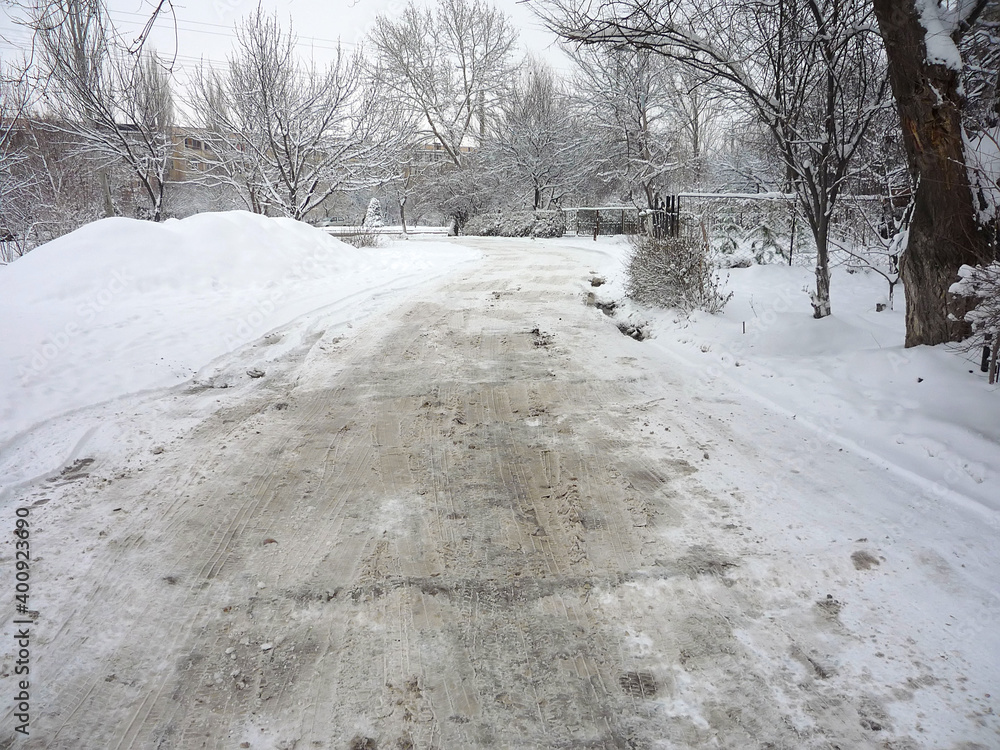 Road through the trees in winter is covered with a thick layer of dirty loose snow Road through the trees in winter is covered with a thick layer of dirty loose snow