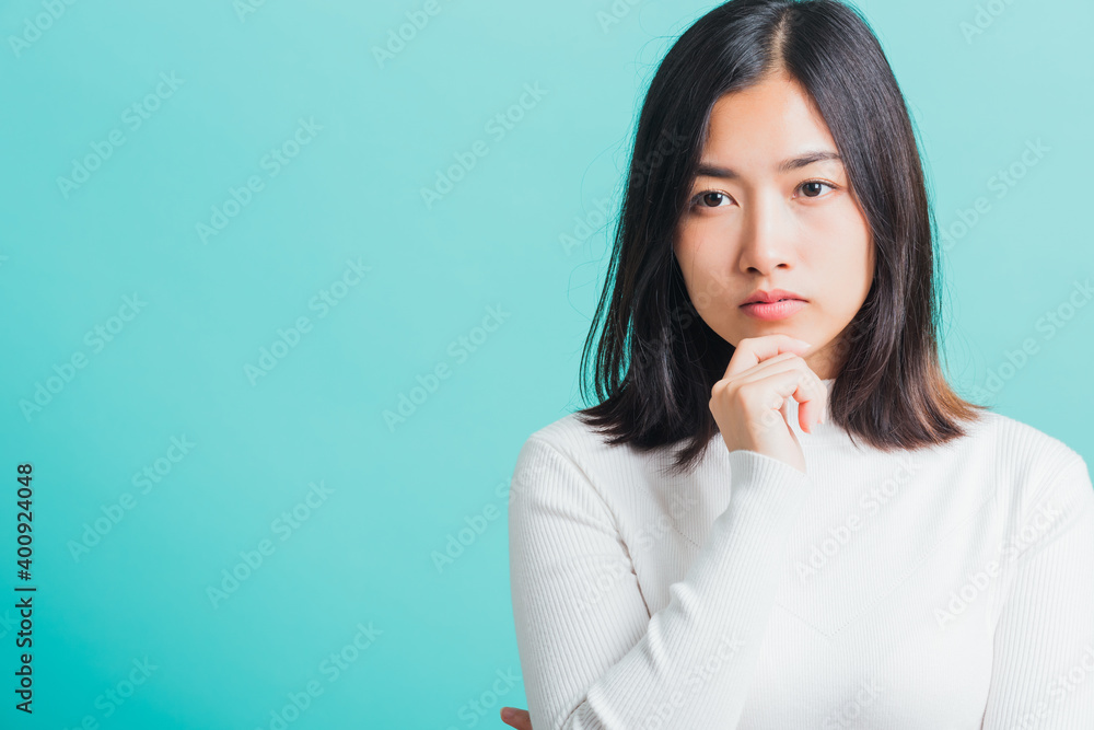 Young beautiful Asian woman hand near the face and thinking, Portrait female touch chin dream dreamy having doubts, studio shot isolated on a blue background Young beautiful Asian woman hand near the face and thinking, Portrait female touch chin dream dreamy having doubts, studio shot isolated on a blue background