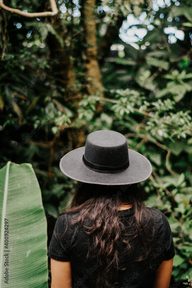 The back of a woman wearing hat in nature.