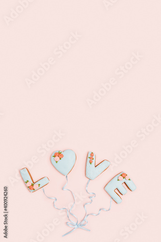 Painted gingerbread in shape of word love as balloons connected by ribbon on pink background witn copy space for your text. Love romance concept.