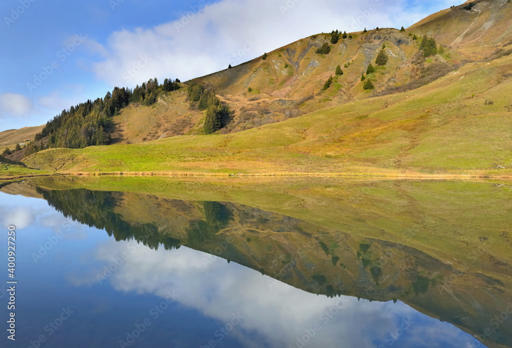 reflection of the sky and landscape on the water of a alpine mountain lake
