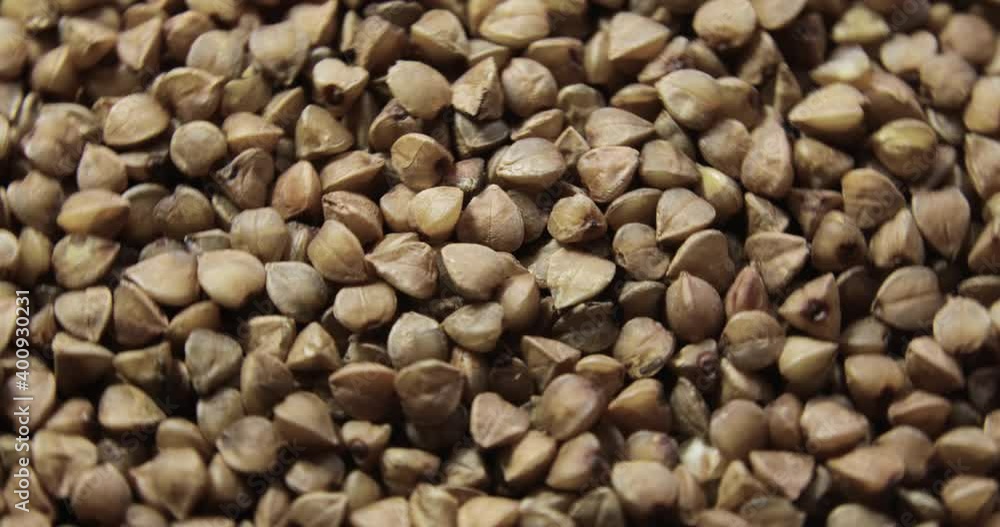 Brown background with fresh grain. Raw buckwheat groat rotating in frame, closeup view. Healthy organic product for vegetarian diet. Brown background with fresh grain. Raw buckwheat groat rotating in frame, closeup view. Healthy organic product for vegetarian diet.