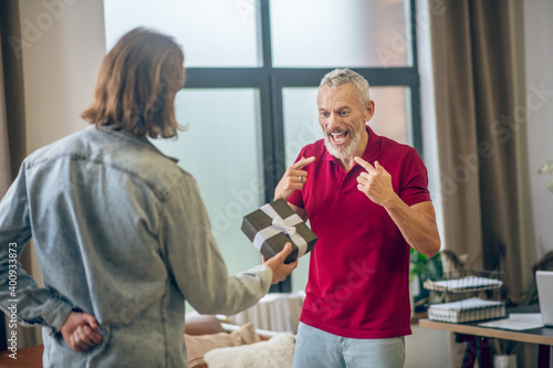 Grey-haired man looking happy receiving a gift from his partner