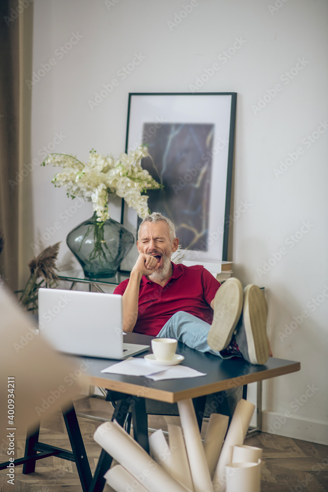Grey-haired man sitting at the laptop and looking bored Grey-haired man sitting at the laptop and looking bored