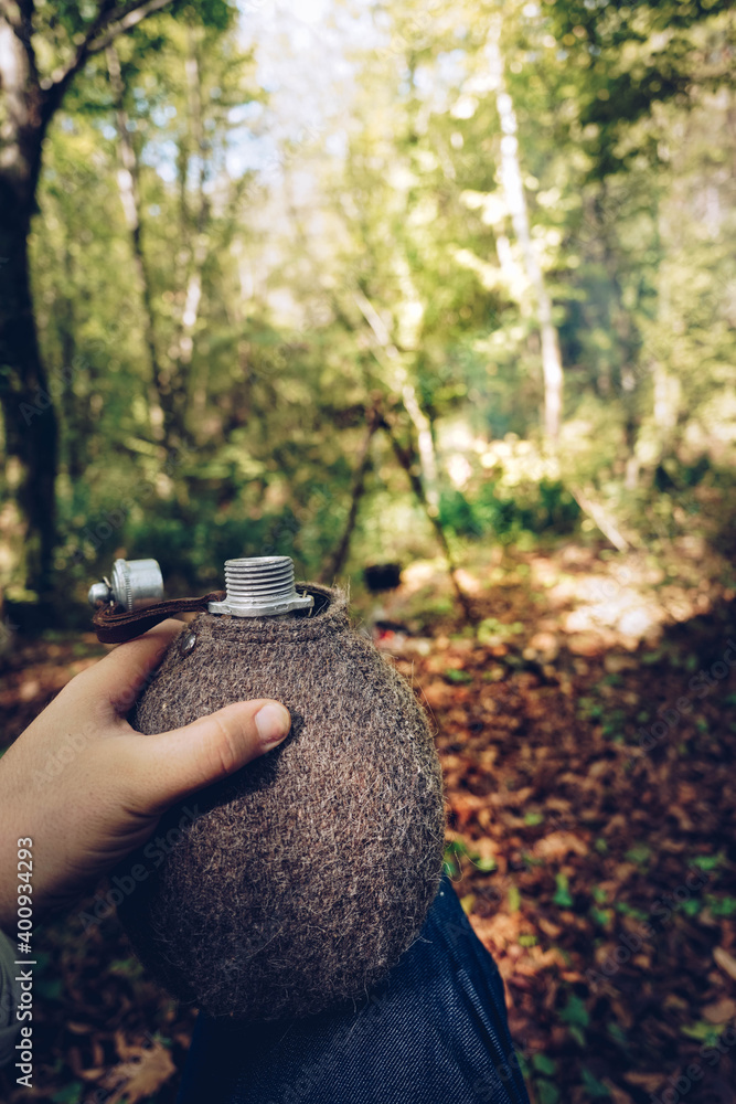 Man in bushcraft with a flask in hand Man in bushcraft with a flask in hand