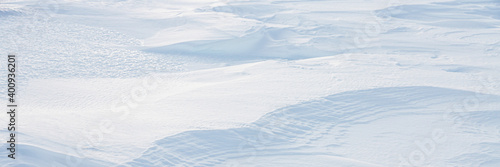 Beautiful winter background with snowy ground. Natural snow texture. Wind sculpted patterns on snow surface. Arctic, Polar region. © Andrei Stepanov