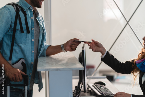 Close up hand of Caucasian airline ground staff in black uniform receive passport from passenger. Concept of normal travel lifestyle after ease in lockdown for Covid-19 Coronavirus pandemic