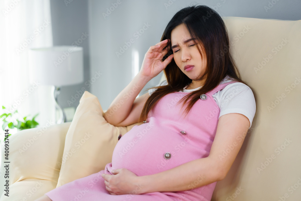 stressed pregnant woman has a headache on sofa in living room stressed pregnant woman has a headache on sofa in living room