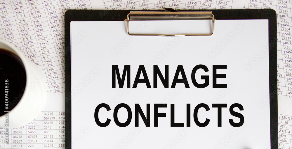 ON the letter tablet, the text is MANAGE CONFLICTS, next to a coffee mug, reports. ON the letter tablet, the text is MANAGE CONFLICTS, next to a coffee mug, reports.