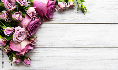 Frame made of pink rose flowers on white wooden background.