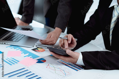 Businessmen use a calculator to calculate company financial statements for their colleagues, view and jointly solve problems within the company. Business finance and accounting concepts