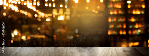 Fotografie top of black wood table with blur lamp light of club or bar at night party banne