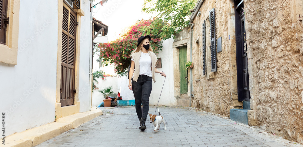 tourist in protective mask holds dog on hands and walking in old city Coronavirus disease COVID-19 new travel reality. Girl in medical mask walking. Coronavirus pandemic Precautions. Travel with pets tourist in protective mask holds dog on hands and walking in old city Coronavirus disease COVID-19 new travel reality. Girl in medical mask walking. Coronavirus pandemic Precautions. Travel with pets