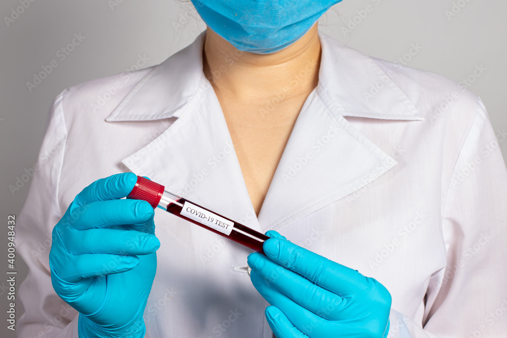 A doctor or lab technician wearing a mask and gloves is holding a blood test tube with the inscription coronavirus test. COVID-19 Diagnostics, Rapid Test, SARS-CoV-2 Virus Detection A doctor or lab technician wearing a mask and gloves is holding a blood test tube with the inscription coronavirus test. COVID-19 Diagnostics, Rapid Test, SARS-CoV-2 Virus Detection