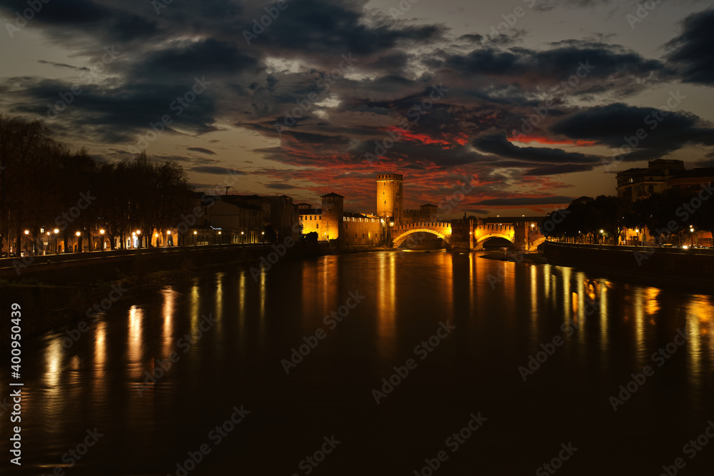 Ponte di Castelvecchio, sunset. Old brick bridge over the Adige river. Historic bridge in Verona, Italy. Reflection of the lights of the city of Verona.