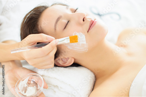 young woman receiving white facial mask in the beauty salon