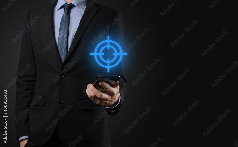 Targeting concept with businessman hand holding target icon dartboard sketch on chalkboard. Objective target and investment goal concept. Targeting concept with businessman hand holding target icon dartboard sketch on chalkboard. Objective target and investment goal concept.