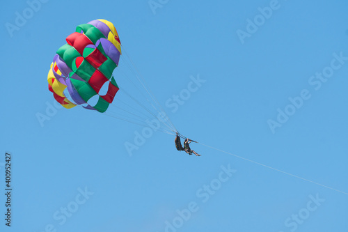 tandem parasailing with two people against a blue sky and an open colourful parachute in Mauritius, concept extreme sports