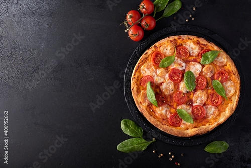homemade pizza with mozzarella and cherry tomatoes on a black round board