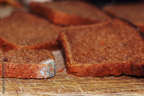Mold on rye bread. Slices of rye bread on a wooden cutting board. Soft selective focus.