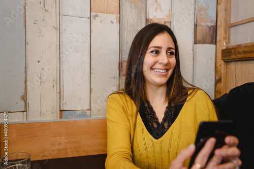 Copy space with close-up young woman with smiling face holding a smartphone and talking with somebody.
