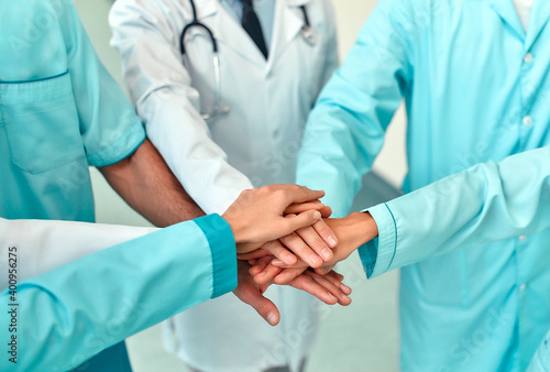 Mature doctors and young nurses stacking hands together at hospital. Close up hands of medical team stacking hands. Group of successful medical doctors and nurses stack of hands.