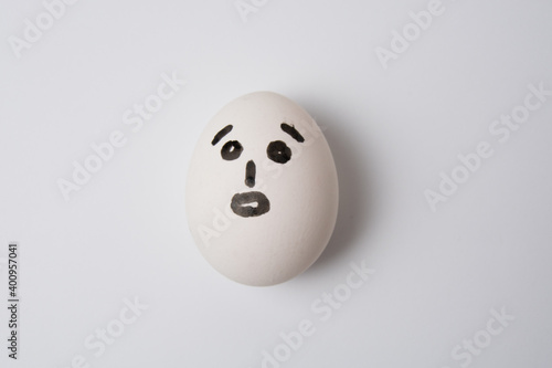 An egg with a surprised face, on a white background copy space.