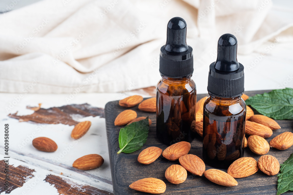 Almond essential oil in dark glass bubbles and fresh almond nuts. Aromatherapy oil natural organic cosmetic. Almond essential oil in dark glass bubbles and fresh almond nuts. Aromatherapy oil natural organic cosmetic.