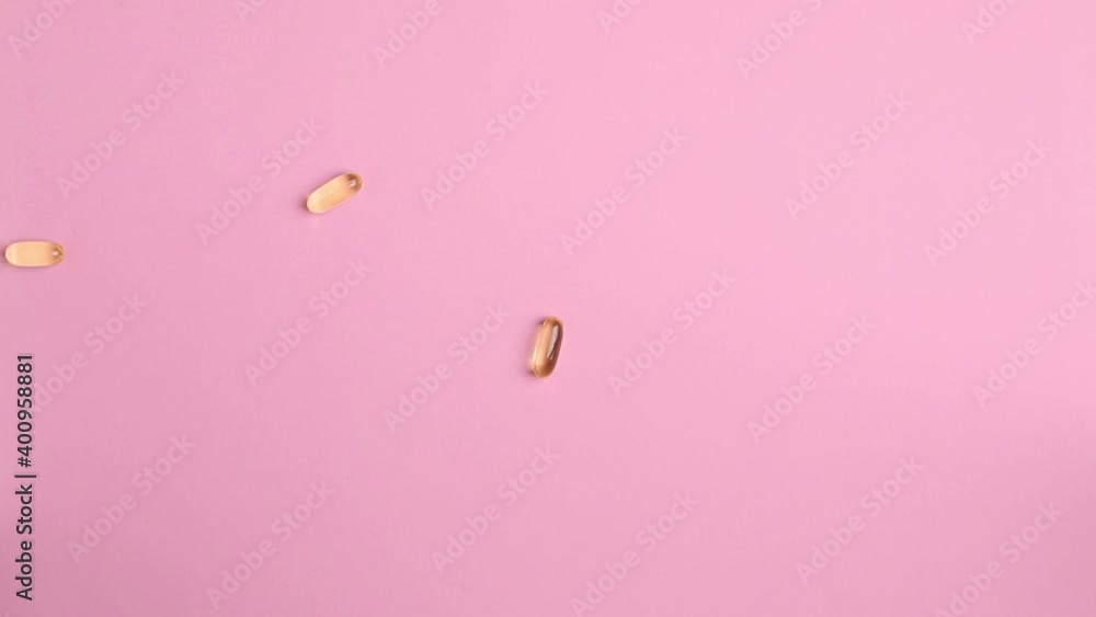 Organic supplements vitamins yellow capsules Omega 3 or D-3 pills on pink background. Dietary supplement top view Organic supplements vitamins yellow capsules Omega 3 or D-3 pills on pink background. Dietary supplement top view