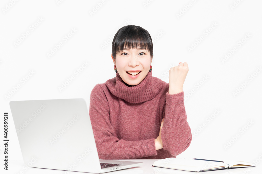 ノートパソコンを使いながらガッツポーズをする女性