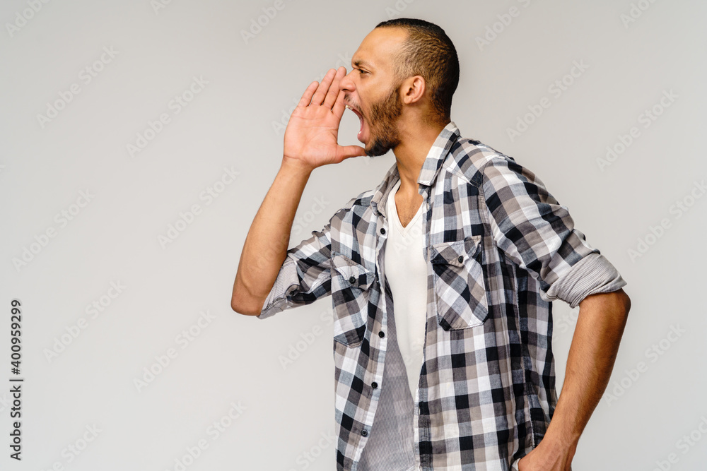 young african american man shouting against a grey background young african american man shouting against a grey background
