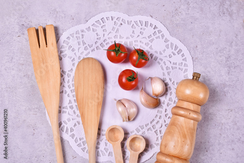 Wooden kitchen tools with red cherry tomato and garlic with peper mill and spices