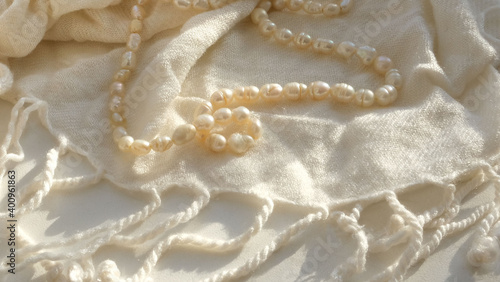 Fotografiet strands freshwater pearls and light beige scarf light and shadow sun rays , copy space