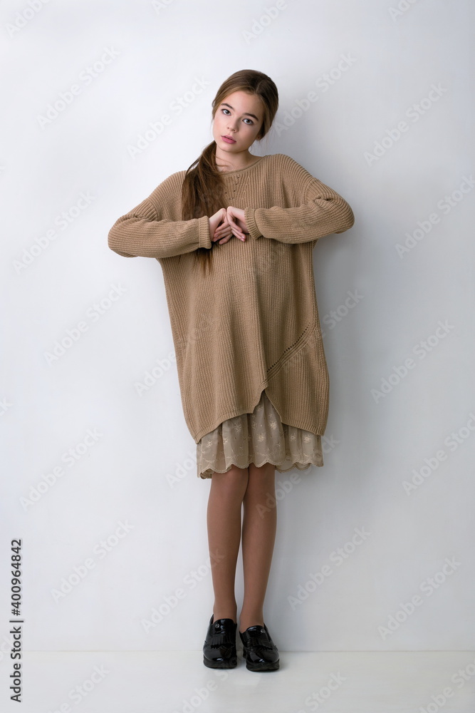 beautiful girl in a stylish dress hoodie posing in the studio near a white wall beautiful girl in a stylish dress hoodie posing in the studio near a white wall