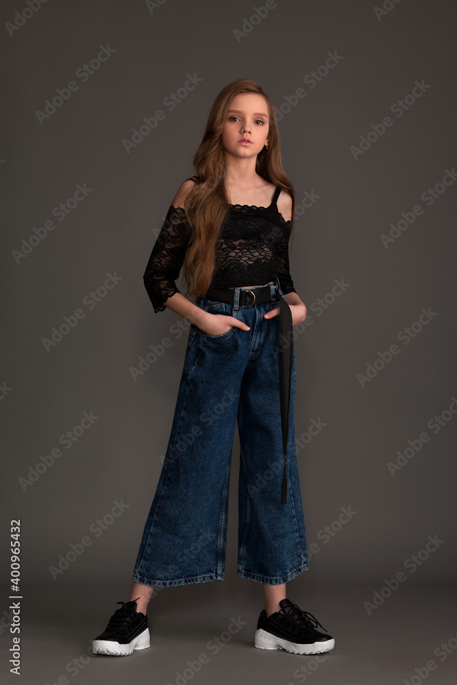 beautiful girl in jeans and a blouse posing in the studio on a gray background beautiful girl in jeans and a blouse posing in the studio on a gray background