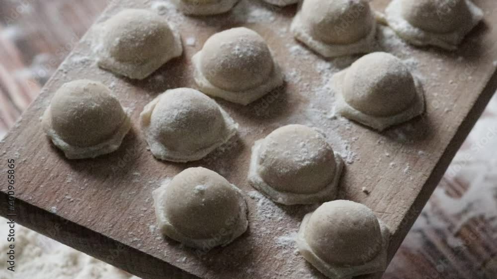 Cooking dumplings. Raw dumplings lie on a wooden board. Nearby lies a rolling pin and dough sprinkled with flour.
Cooking dumplings. Raw dumplings lie on a wooden board. Nearby lies a rolling pin and dough sprinkled with flour.