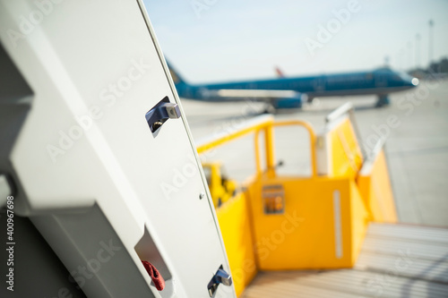 Open door to a large airliner as seen from inside. Aircraft door frame, door handle and door barrier strap