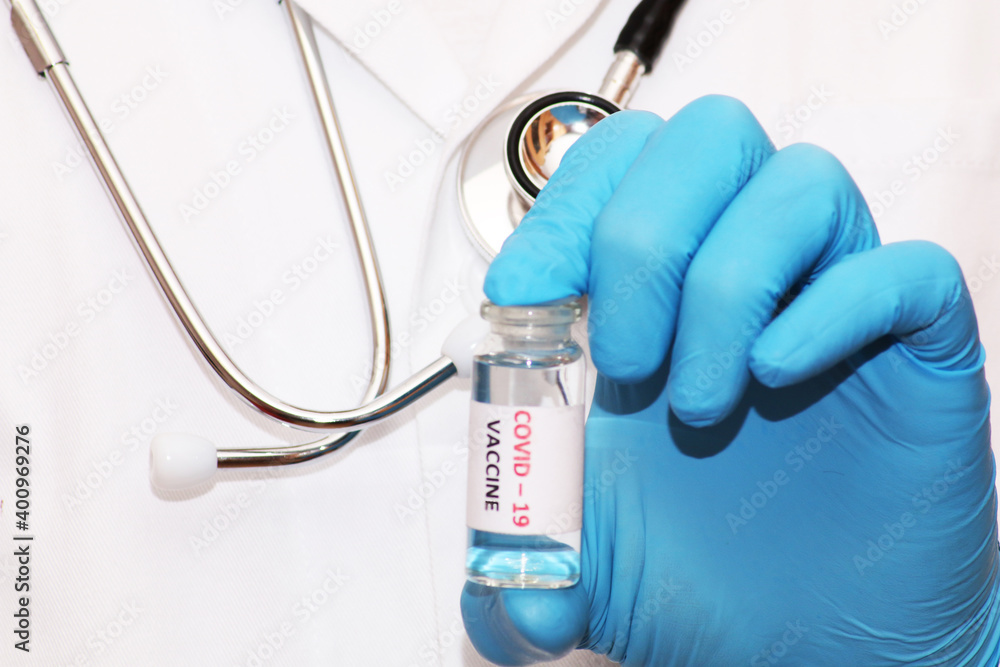 Fototapeta premium Covid-19 corona virus fight concept. The doctor is ready to vaccinate against coronavirus, holds a syringe and vaccine in his hands. Concept: disease, medical care, science.
