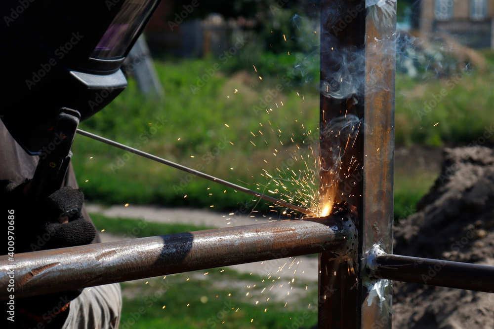 male welder welds iron parts at construction male welder welds iron parts at construction