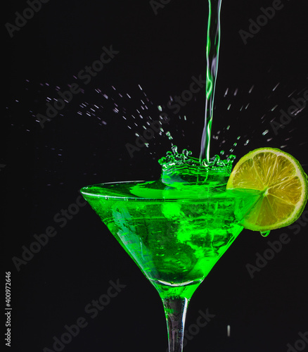 Green drink in a glass. Green water or limnad. A splash of green liquid similar to absinthe. Alcohol and alcoholism. photo