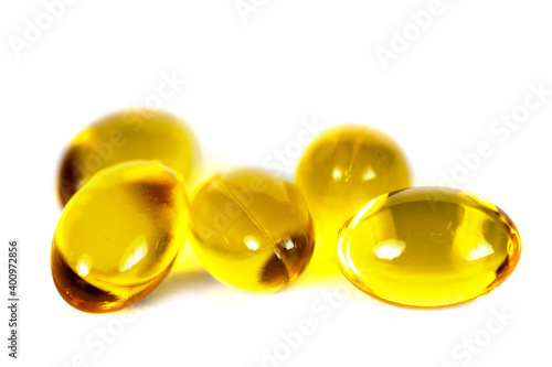 Yellow capsules of vitamin D, macro close-up of golden pills isolated on white