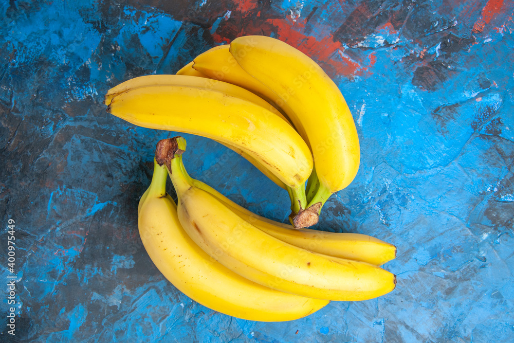Above view of two bunches of fresh natural cavendish bananas on isolated blue background Above view of two bunches of fresh natural cavendish bananas on isolated blue background