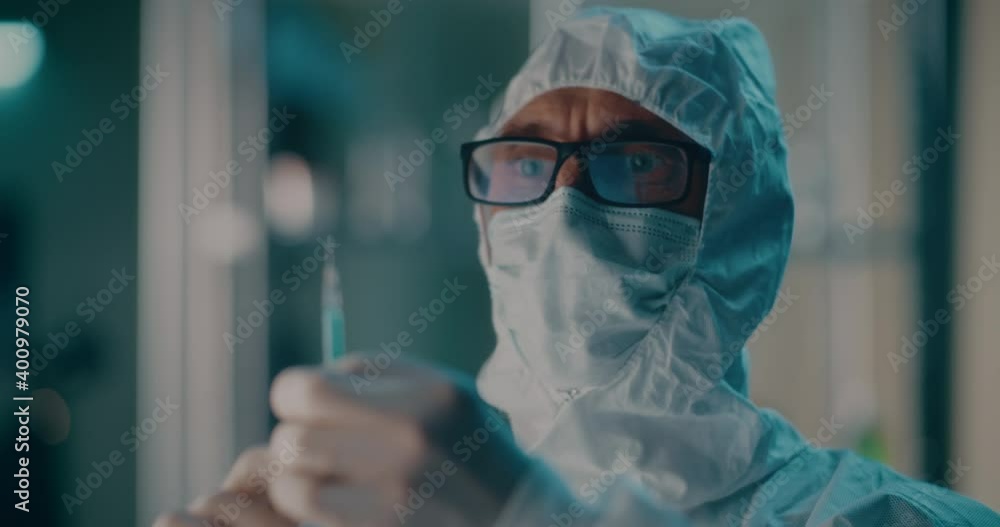 Doctor in hazmat suit preparing syringe with vaccine Doctor in hazmat suit preparing syringe with vaccine