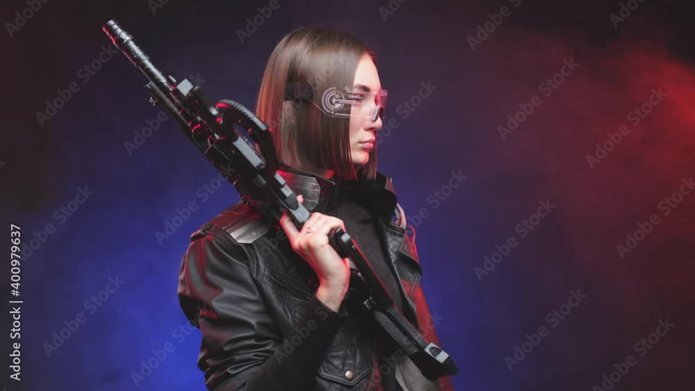 Dressed in black leather jacket martial woman with glasses and cyber implant on her shoulder rotates slowly with rifle on her shoulder in smokey background. Futuristic portrait of a stylish woman