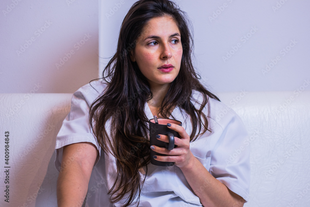 Mujer enfermera descansando en un sofá bebiendo de una taza Mujer enfermera descansando en un sofá bebiendo de una taza