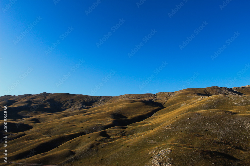 Mountain in the fall before sunset. Landscape of Bjelasnica mountain, meadows, pastures, grass, stones, sky. Simple but magnificent landscape view.