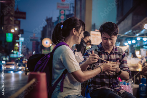 Photography Asian couple eating in Street food Night market for tourist on chinatown at yaow