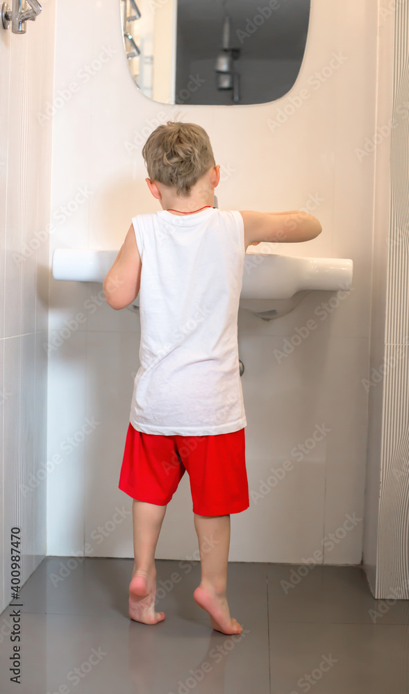 Child stands near the sink and washes his hands. Child stands near the sink and washes his hands.