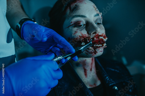 Valokuva Woman in image of mutant pull a tooth out in dental clinic.